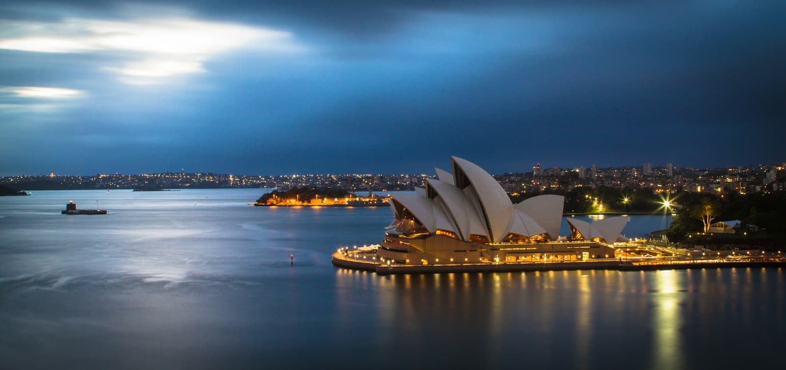 Sydney Opera House lit up on the harbour at dusk