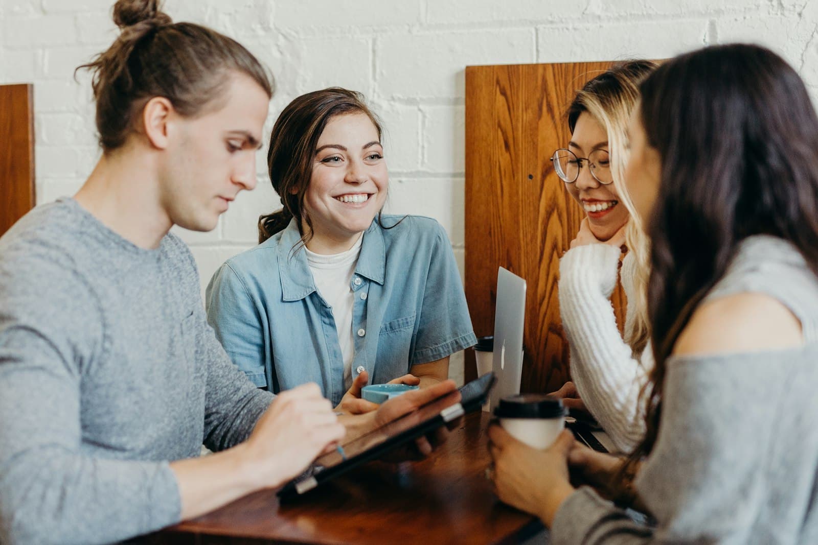 Four students smiling over a laptop at a shared table