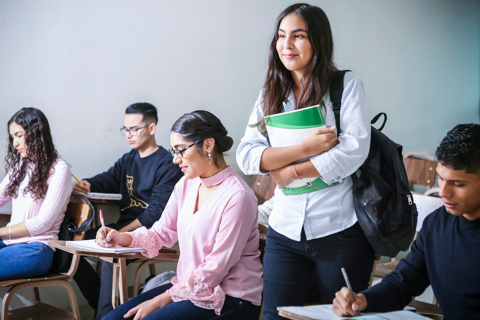 A student standing with her notes among classmates in a classroom